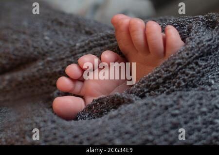 Pieds de bébé sur une couverture gris foncé, en gros plan. Banque D'Images