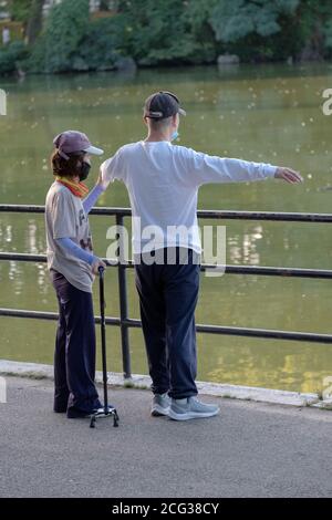 Un aide aide aide un homme ayant des problèmes de santé à faire sa routine d'étirement. Dans un parc à Flushing, Queens, New York. Banque D'Images