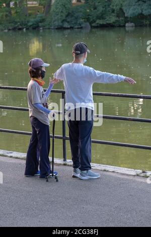 Un aide aide aide un homme ayant des problèmes de santé à faire sa routine d'étirement. Dans un parc à Flushing, Queens, New York. Banque D'Images