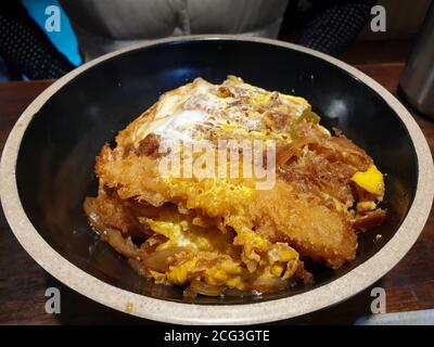 Katsu-don, un bol de riz recouvert d'un côtelette de porc frite, d'œufs, de légumes et de condiments. Également avec EBI Furai, crevettes frites au Japon. Banque D'Images