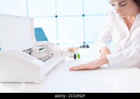 Jeune femme au bureau d'impression du papier et insérez des têtes d'impression couleur sur plotter Banque D'Images