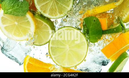 Tranches de citron, d'orange et de lime tombant sous l'eau isolées sur fond blanc Banque D'Images