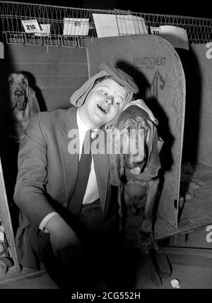 Benny Hill, avec Bloodlag Hector, joué par le chien de Benny Hill, Fabian, dans son film de comédie « Who Cone IT? ». Dans le film, Benny joue un détective privé au spectacle canin du Cruft à Olympia, Londres. Banque D'Images