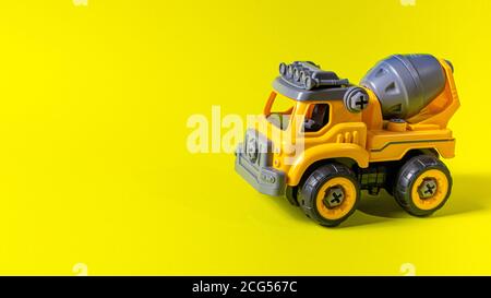 Machine à écrire en jouet avec mélangeur en béton orange sur fond jaune. Une bannière avec un emplacement pour le texte d'un magasin de jouets. Banque D'Images