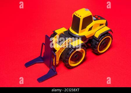 La machine à écrire jaune noir à jouets pour chariot élévateur sur fond rouge. Tracteur d'équipement de construction pour enfants. Banque D'Images