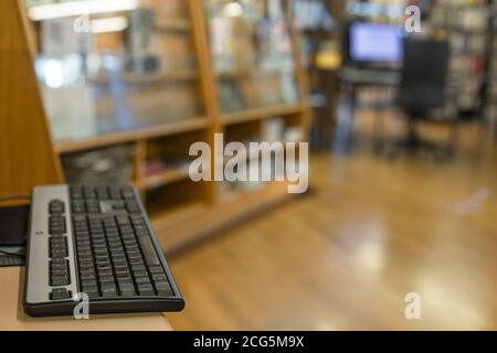 Clavier sur un bureau dans un espace ouvert avec un autre poste de travail présenté en arrière-plan flou Banque D'Images