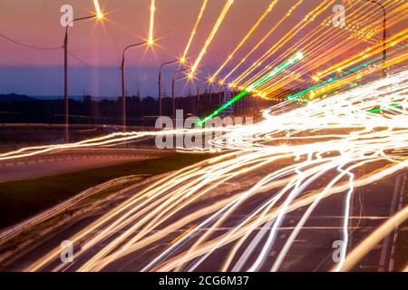 Traces de phares des voitures se déplaçant la nuit sur le pont, illuminés par des lanternes. Paysage urbain abstrait avec autoroute. Banque D'Images