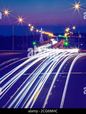Traces de phares des voitures se déplaçant la nuit sur le pont, illuminés par des lanternes. Paysage urbain abstrait avec autoroute. Banque D'Images