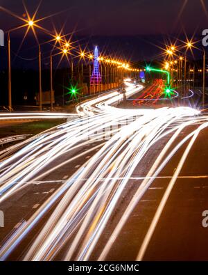 Traces de phares des voitures se déplaçant la nuit sur le pont, illuminés par des lanternes. Paysage urbain abstrait avec autoroute. Banque D'Images