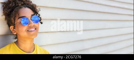 Panorama fille adolescente adolescent mixte race biracial Afro-américaine femelle jeune femme portant un t-shirt jaune et des lunettes de soleil reflétant le ciel bleu Banque D'Images