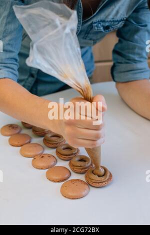 Femme remplissant des macarons au chocolat de ganache au chocolat Banque D'Images