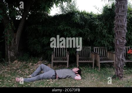 Homme couché sur l'herbe dans un jardin, France Banque D'Images