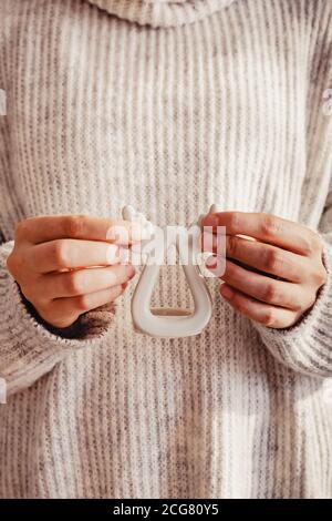 Mains féminines tenant un bougeoir en forme de cerf gros plan. Femme en pull confortable avec décor de Noël. Banque D'Images