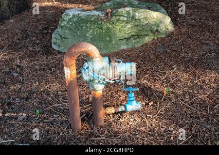 Un ancien tuyau d'eau bouché et rouillé avec soupape et chaîne se dévie à l'extérieur Banque D'Images