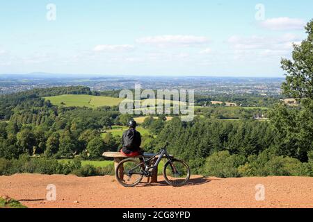 Cycliste assis sur un banc et bénéficiant de la vue depuis les collines de Cent, Worcestershire, Angleterre, Royaume-Uni. Banque D'Images