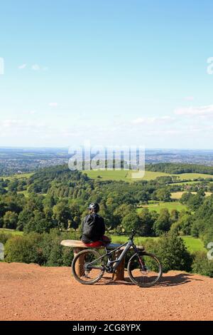 Cycliste assis sur un banc et bénéficiant de la vue depuis les collines de Cent, Worcestershire, Angleterre, Royaume-Uni. Banque D'Images