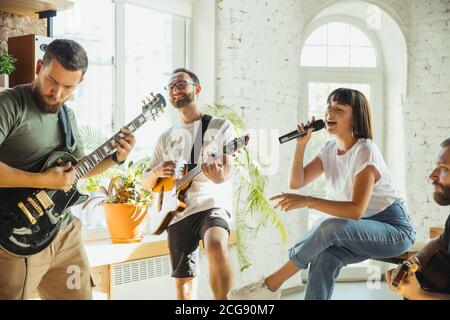 Rythme. Le groupe de musiciens s'est rassemblé sur le lieu de travail de l'art avec des instruments. Hommes et femmes caucasiens, musiciens, jouant et chantant ensemble. Concept de musique, passe-temps, émotions, métier artistique. Banque D'Images