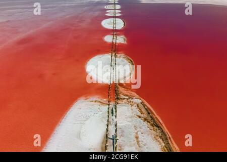 Vue aérienne de dessus incroyable lac rose droit. Salar avec poutres en bois et îles de sel dans le centre. Banque D'Images