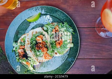 Tacos aux crevettes, avocat et salade verte sur une assiette verte, vue du dessus Banque D'Images