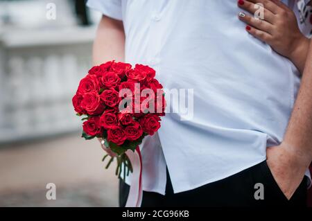 bouquet de roses rouges dans les mains du marié Banque D'Images