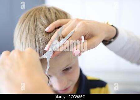 Le coiffeur principal coupe les langes du garçon blond. Banque D'Images