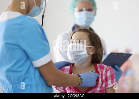 Le médecin écoute la respiration d'une fille avec un stéthoscope à la réception clinique Banque D'Images