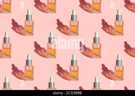 Modèle sans couture de bouteille de verre avec des cosmétiques d'extrait d'huile de graines naturelles organiques pour le soin de la peau et des cheveux sur fond rose pastel. Spa de beauté minimal Banque D'Images