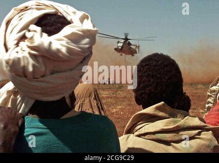 1993 - tourné sur les épaules de certains Somaliens regardant un Marine américain CH-53 Sea Stallion helicopter offrir une charge de blé dans un champ près du village de Maleel, en Somalie. La livraison de l'a fait don de la Commission australienne du blé a été un effort de coopération entre les Marines américains, qui ont fourni l'hélicoptère, et l'armée australienne, qui a fourni la sécurité. Certains membres du personnel des Forces australiennes sont vus avec des gens près de la zone de dépôt. Le "Red Lions" de l'Escadron d'hélicoptères lourds Marine 363 de Tustin, Californie voler les hélicoptères. Banque D'Images