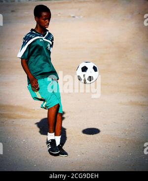 Un garçon de la ville de Djibouti orphelinat du garçon un ballon de soccer coups donnés par les membres de l'armée américaine déployés avec la Force opérationnelle interarmées - Corne de l'Afrique (CJTF-HOA). - Corne de l'Afrique est une unité de commandement central des États-Unis qui mène des opérations et de la formation pour aider les pays partenaires à lutter contre le terrorisme afin d'établir un environnement sûr et permettre à la stabilité régionale. Banque D'Images