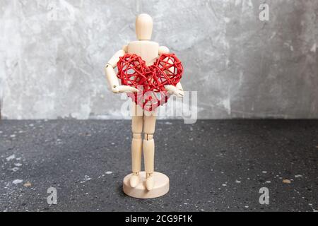 Mannequin en bois avec coeur en rotin rouge. Banque D'Images