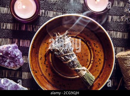 Bâtonnets de lavande à base de plantes maison (lavendula) couvant sur une plaque brune avec des bougies et des grappes de cristal améthyste pour la décoration. Maison spirituelle Banque D'Images