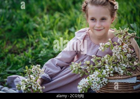 Belle fille de 6-7 ans posant dans le jardin. Pâques. Aime le printemps et la chaleur. Beau jardin de printemps. Bonne enfance, paix et bonheur con Banque D'Images