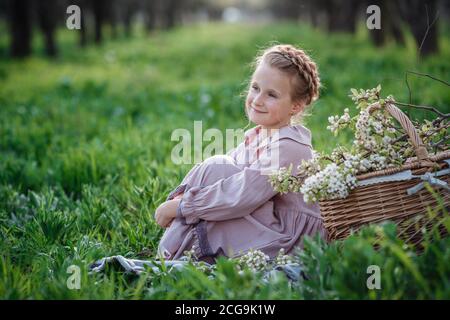 Belle fille de 6-7 ans posant dans le jardin. Pâques. Aime le printemps et la chaleur. Beau jardin de printemps. Bonne enfance, paix et bonheur con Banque D'Images