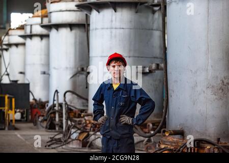 Jeune métallurgiste caucasien posant dans l'atelier de l'usine de métallurgie du titane. Sur le fond du four sous vide. Banque D'Images