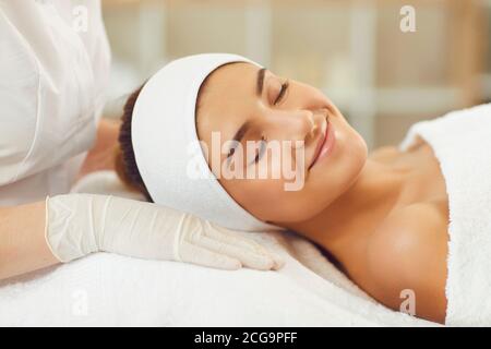 Jeune femme souriant avec les yeux fermés, allongé sur le lit du spa après les procédures de soin de la peau Banque D'Images