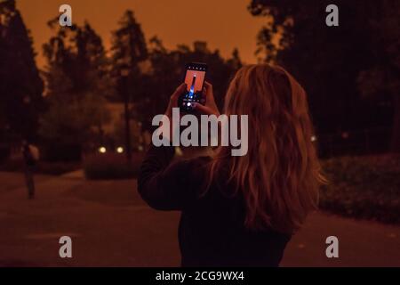 Un étudiant de l'UC Berkeley prend une photo du Campanile lors d'une journée remplie de brume lorsque le ciel est devenu orange à la suite de la fumée des feux de forêt. Banque D'Images