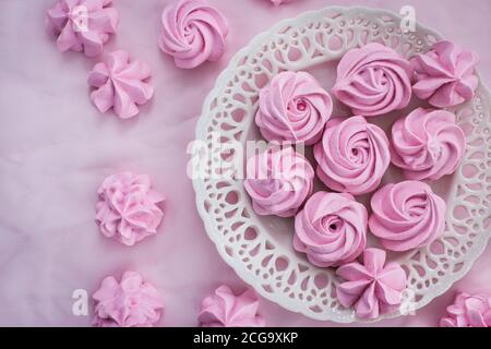 Meringues roses sur l'assiette, fond coloré, vue du dessus Banque D'Images