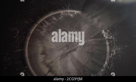 L'eau est versée dans un seau noir. L'eau est versée dans un seau en plastique noir. Gros plan - l'eau est versée dans un seau de construction. Banque D'Images