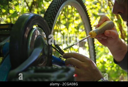 Prendre soin du vélo à l'extérieur. Réparation de la chaîne sur un pignon sur une bicyclette. Banque D'Images