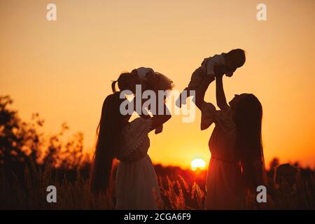 joyeux jeunes mamans jouant avec leurs enfants en plein air en été. Un concept de « famille heureuse ». Foyer sélectif. Banque D'Images