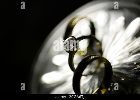 Belle photo aux tons avec des anneaux de mariage sur un bois surface sur le fond d'un bouquet de fleurs Banque D'Images