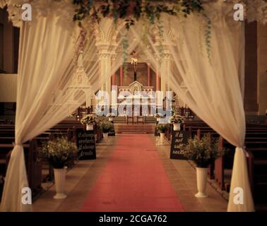 Intérieur de mariage d'église avec rangées de chaises élégantes et arrangements de fleurs fluides. Banque D'Images