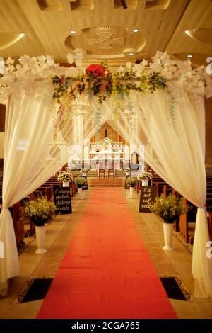 Intérieur de mariage d'église avec rangées de chaises élégantes et arrangements de fleurs fluides. Banque D'Images