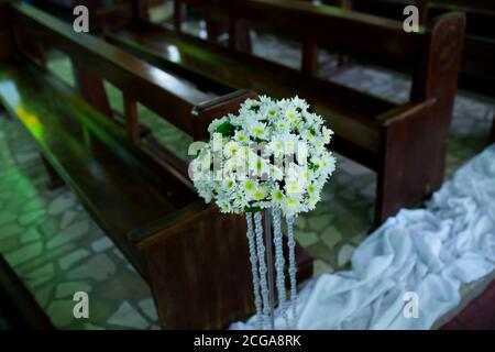 Intérieur de mariage d'église avec rangées de chaises élégantes et arrangements de fleurs fluides. Banque D'Images