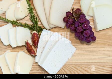 Tranches de fromage de différentes variétés de raisins et figues le fond d'une planche en bois Banque D'Images