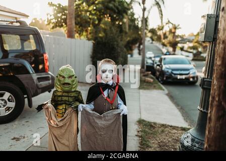 Jeunes frères et sœurs vêtus de costumes d'Halloween pendant le trick-or-Treat Banque D'Images