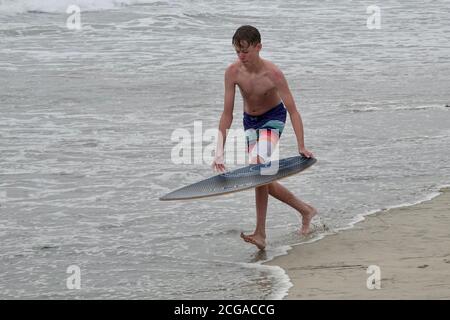 Un adolescent monte sur les vagues les plus proches du rivage de la plage. Banque D'Images