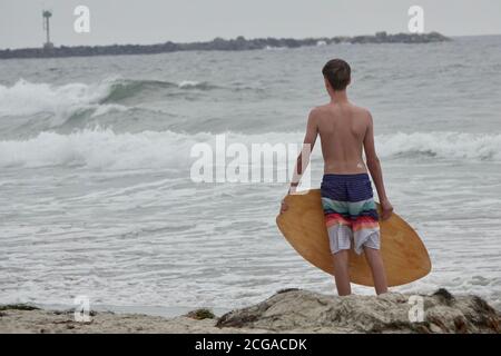 Un adolescent monte sur les vagues les plus proches du rivage de la plage. Banque D'Images