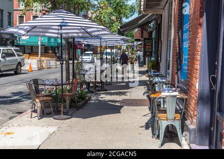 New York, NY - AOÛT 26 2020 : un café-terrasse à la mode avec parasols à rayures à Greenwich Village, NYC. Banque D'Images