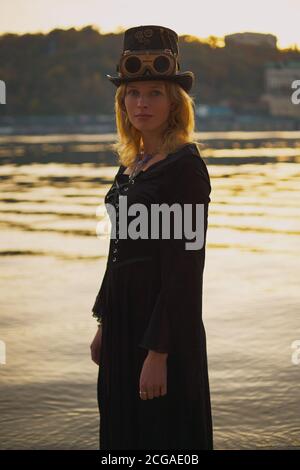 Femme en costume d'halloween près de la rivière au coucher du soleil. Banque D'Images